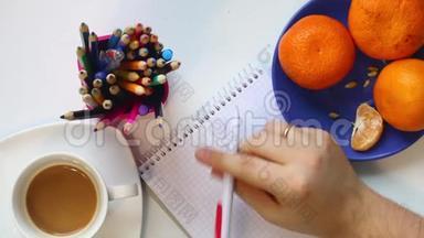 一个男人从桌子上的杯子里喝咖啡。 然后他拿起一支笔，思考在笔记本上写什么。 不时地h